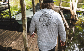 Man wearing a hooded men’s UV sun shirt on a dock at Blueline Surf and Paddle near Trapper Nelson’s on the Loxahatchee River in Jupiter, Florida