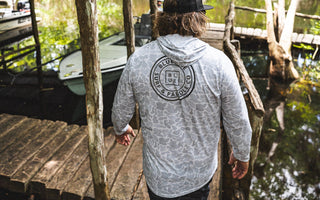 Man wearing a hooded men’s UV sun shirt on a dock at Blueline Surf and Paddle near Trapper Nelson’s on the Loxahatchee River in Jupiter, Florida