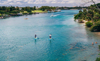 Two paddlers on paddleboard rentals in Jupiter, Florida, exploring the clear blue water of the Intracoastal near Coral Cove and the Jupiter Lighthouse..