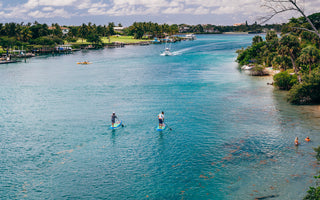 Two paddlers on paddleboard rentals in Jupiter, Florida, exploring the clear blue water of the Intracoastal near Coral Cove and the Jupiter Lighthouse..