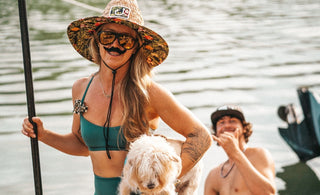 Paddleboarder wearing a sombrero and fake mustache holds a small dog while posing on the dock during the Cinco De Mayo themed Tuesday Night Race League event at Guanabanas in Jupiter, Florida.