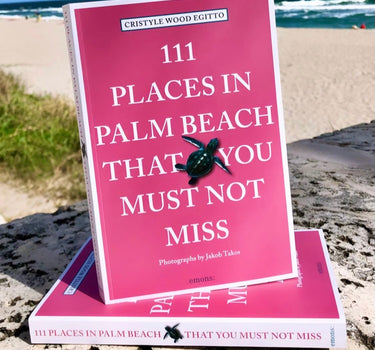 Book titled “111 Places in Palm Beach That You Must Not Miss” displayed outdoors near the beach in Palm Beach County, Florida.