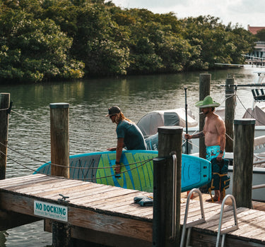 Dock hand preparing stand-up paddleboard rental at the Blueline Surf & Paddle Co. floating dock at Guanabanas in Jupiter, Florida, for the Tuesday Night Race League.
