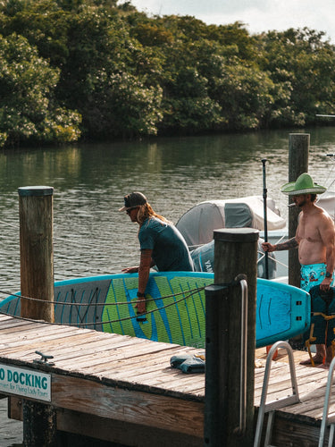 Dock hand preparing stand-up paddleboard rental at the Blueline Surf & Paddle Co. floating dock at Guanabanas in Jupiter, Florida, for the Tuesday Night Race League.