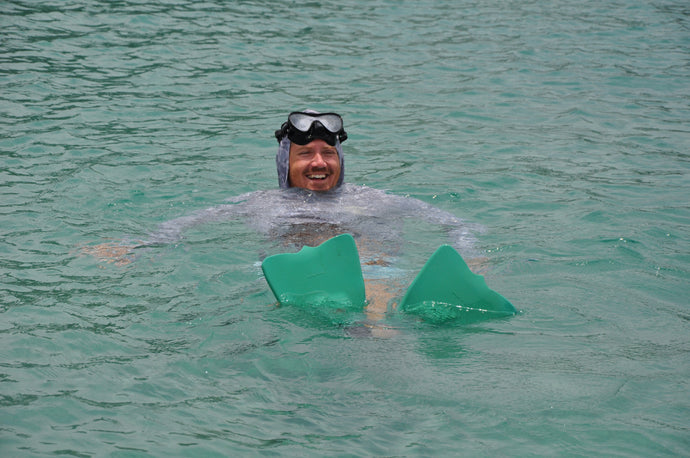 A man snorkeling in clear blue South Florida water wearing a diving mask and flippers, enjoying a summer holiday boat and sandbar day out by the Jupiter Inlet.