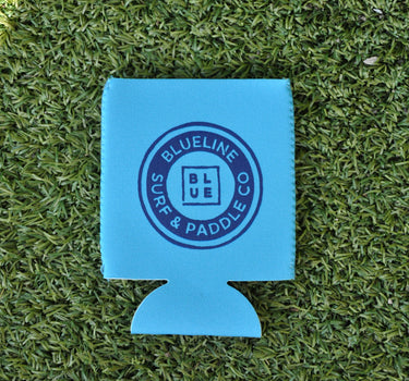 Neon blue Blueline Surf & Paddle Co. neoprene koozie with navy logo on grass