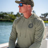 Man wearing Vintage Blueline Logo ANETIK Low Pro Tech Hoody in olive while boating in Jupiter, Florida