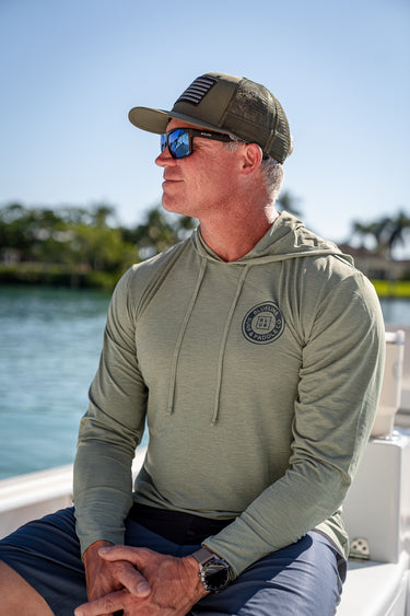 Man wearing Vintage Blueline Logo ANETIK Low Pro Tech Hoody in olive while boating in Jupiter, Florida