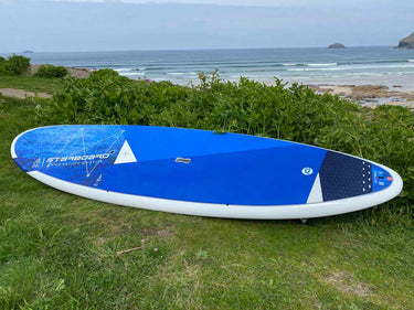 2023 Starboard Go Surf resting on green grass with a beach and ocean in the background.