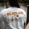 Image of the Blueline Surf & Paddle Co. fly fishing T-shirt featuring a guide poling on a skiff with an angler casting at sunset in Jupiter, Florida. The back drop is the intracoastal in Palm Beach County Florida.