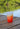 A silicone shot glass with a Blueline Surf and Paddle diamond logo in marigold. Sitting on a dock in Palm Beach County. 