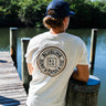 Man wearing OG Blueline Logo T-Shirt in washed natural standing on a dock in Jupiter, Florida