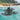 Olukai Ohana Black sandals floating in clear blue water.