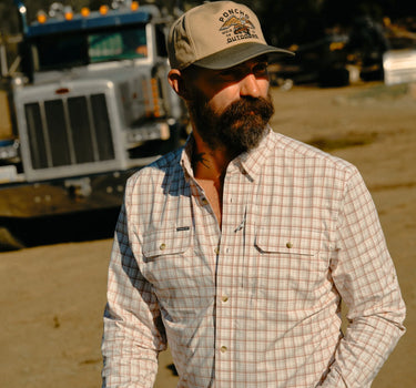 Man wearing Poncho Long Nose Pete plaid button-down shirt outdoors