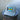 Gray Bahamas flag trucker hat by Blueline Surf & Paddle photographed on a dock piling overlooking calm waterfront waters in Jupiter Florida.