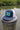 Navy and white Bahamas flag trucker hat by Blueline Surf & Paddle photographed on a dock piling overlooking the Jupiter Florida waterfront.