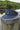 Navy Imperial Tour Visor featuring an embroidered Jupiter Lighthouse on the front and a classic high-profile design, photographed on a dock piling in Jupiter, Florida.