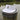 White Imperial Tour Visor featuring an embroidered Jupiter Lighthouse on the front and a classic high-profile design, photographed on a dock piling in Jupiter, Florida.