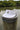 White Imperial Tour Visor featuring an embroidered Jupiter Lighthouse on the front and a classic high-profile design, photographed on a dock piling in Jupiter, Florida.