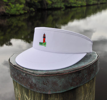 White Imperial Tour Visor featuring an embroidered Jupiter Lighthouse on the front and a classic high-profile design, photographed on a dock piling in Jupiter, Florida.