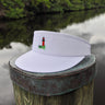 White Imperial Tour Visor featuring an embroidered Jupiter Lighthouse on the front and a classic high-profile design, photographed on a dock piling in Jupiter, Florida.