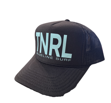 The official Blueline 2025 TNRL Foam Hat displayed at the surf shop counter in Jupiter, Florida, featuring the limited-edition Tuesday Night Race League graphic and breathable mesh backing.