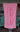Blueline Beach Towel in pink featuring the vertical Blueline logo, displayed outside Blueline Surf & Paddle Co. in Jupiter, Florida.