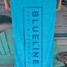 Blueline Beach Towel in turquoise featuring the vertical Blueline logo displayed outside Blueline Surf & Paddle Co. in Jupiter, Florida.