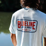 Back view of a man wearing an ice blue Blueline Classic Badge T-shirt with large back logo, standing near the water in Jupiter, Florida.