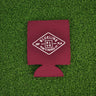 Maroon neoprene Blueline diamond logo koozie with white print displayed on grass