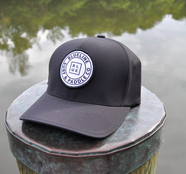 Black Blueline FlexFit performance hat featuring the embroidered Blueline Circle Logo, designed for boating, golf, paddleboarding, fishing, and outdoor adventures in Jupiter, Florida.