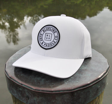 White Blueline FlexFit performance hat featuring the embroidered Blueline Circle Logo, designed for boating, golf, paddleboarding, fishing, and outdoor adventures in Jupiter, Florida.