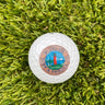 Blueline Lighthouse logo golf ball resting on green grass, featuring the Jupiter Lighthouse design.
