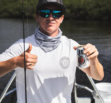 Man wearing a white and gray Blueline OG Circle short sleeve UV sun shirt holding fishing gear on a boat in Jupiter, Florida.