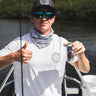 Man wearing a white and gray Blueline OG Circle short sleeve UV sun shirt holding fishing gear on a boat in Jupiter, Florida.