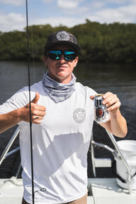 Man wearing a white and gray Blueline OG Circle short sleeve UV sun shirt holding fishing gear on a boat in Jupiter, Florida.
