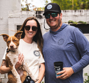 Couple wearing Blueline OG Circle UV sun hoodies in heather denim and true navy standing outdoors in Jupiter, Florida.