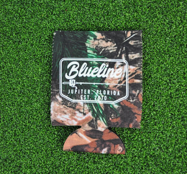 Tree camo neoprene Blueline Rod & Reel logo koozie with white print displayed on grass