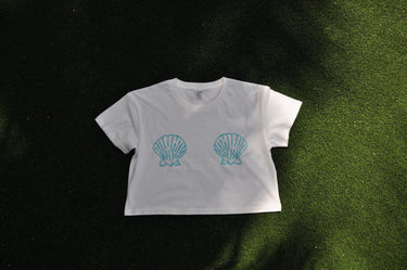Front and back view of the Blueline Shell Crop Tee in natural featuring a left chest logo and large shell graphic on the back.
