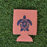 Pink neoprene Blueline turtle logo koozie with navy print displayed on grass