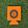 Orange neoprene Blueline Vintage Circle logo koozie displayed on grass