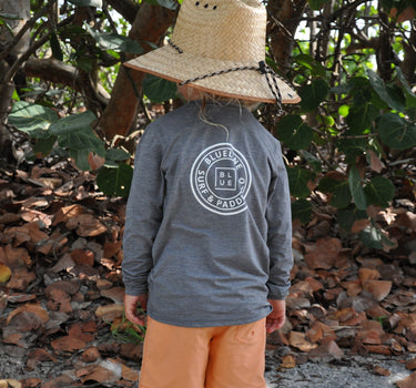 Child wearing the Blueline Youth OG Logo Long Sleeve UV Sun Shirt | Dark Grey while exploring the beach in Jupiter, Florida.