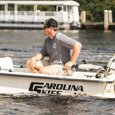 Man wearing a heather dark gray Blueline OG Circle short sleeve UV sun shirt stepping onto a skiff in Jupiter, Florida.