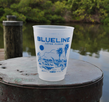 Blueline Surf & Paddle Gator Lasso Rum Runner Cup featuring a cowgirl lassoing an alligator with Florida palmetto trees in the background – reusable 16 oz frosted cup from Jupiter, Florida surf shop.