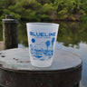 Blueline Surf & Paddle Gator Lasso Rum Runner Cup featuring a cowgirl lassoing an alligator with Florida palmetto trees in the background – reusable 16 oz frosted cup from Jupiter, Florida surf shop.