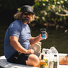 Man wearing a heather denim Blueline OG Circle short sleeve UV sun shirt sitting on a skiff in Jupiter, Florida.