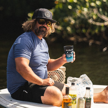 Man wearing a heather denim Blueline OG Circle short sleeve UV sun shirt sitting on a skiff in Jupiter, Florida.