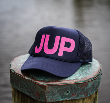 JUP Pink Logo Hat by Blueline Surf & Paddle Co. in Jupiter, Florida, featuring bold pink JUP letters on navy mesh snapback hat.