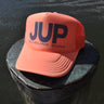 JUP coral trucker hat on dock by the water in Jupiter Florida