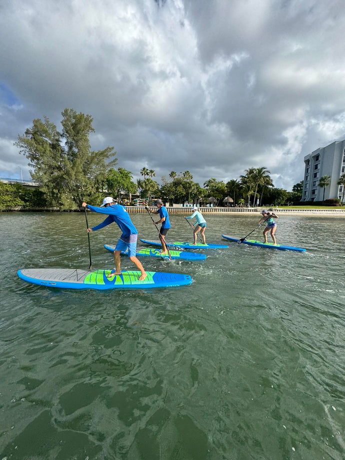 Beginner-friendly kayak and paddleboard rental group paddling in calm Intracoastal waters near Burt Reynolds Island in Jupiter Florida.